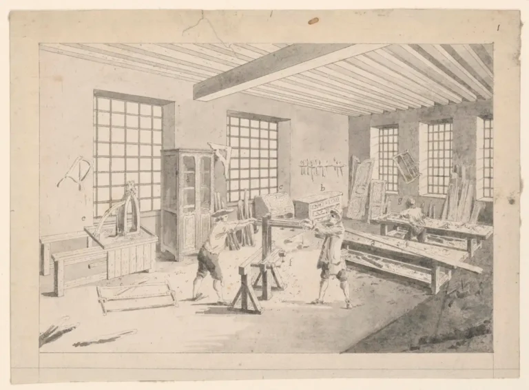 Cabinet maker holding a brad nailer beside unfinished cabinet doors in a bright workshop