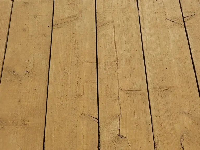 Carpenter beside pressure-treated deck framing with deck screws and fasteners on a workbench