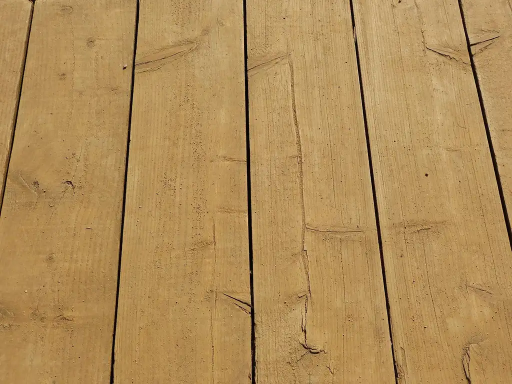 Carpenter beside pressure-treated deck framing with deck screws and fasteners on a workbench