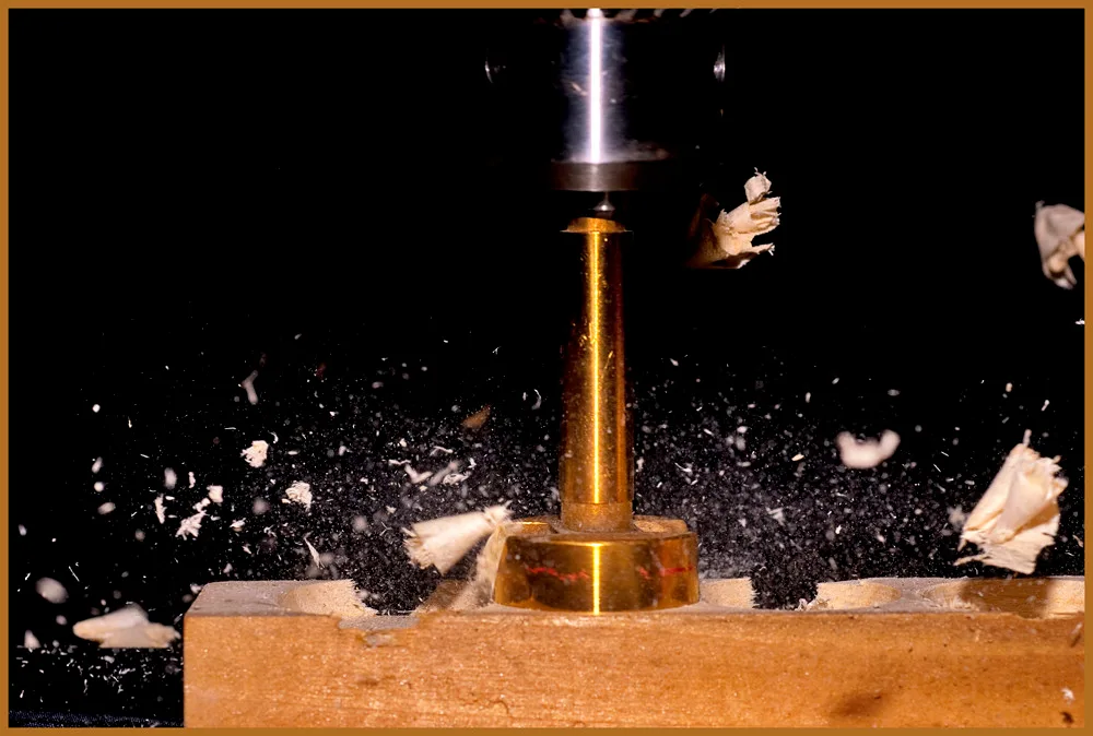 Hand comparing a drill bit to a marked hardwood board for woodworking
