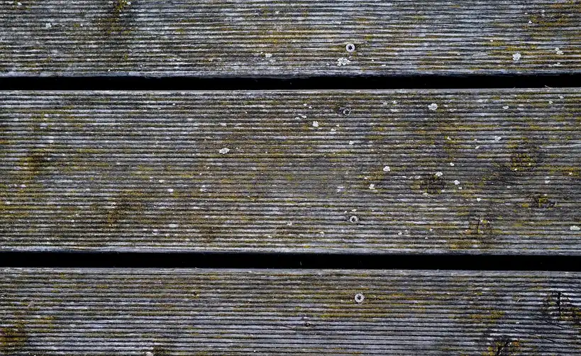 Exterior wood screws and deck boards laid out on a workbench beside a partially built deck