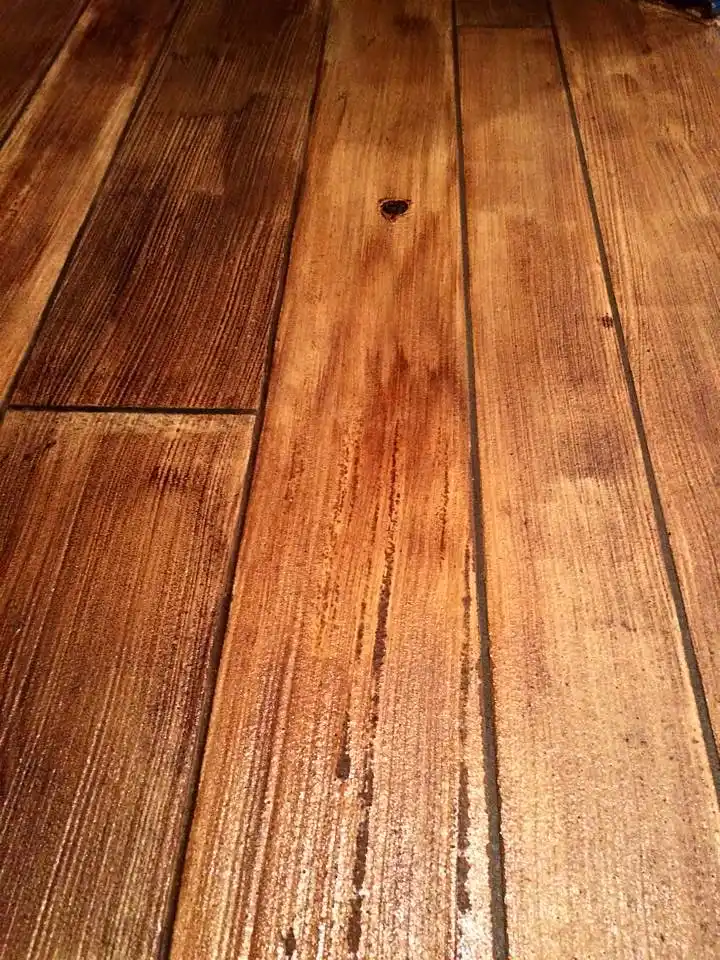 A brush applying semi-transparent exterior wood stain to cedar fence boards