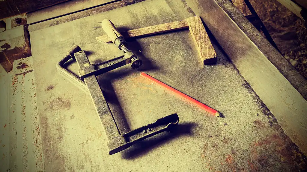Carpenter choosing a nail gun beside trim boards, hardwood samples, and a workbench