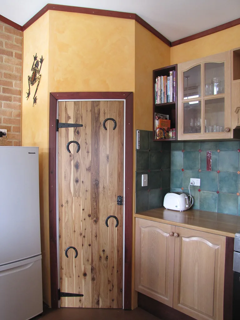 Paint sprayer beside primed cabinet doors in a bright workshop