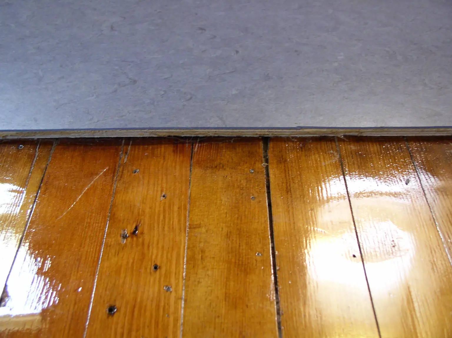 Hands measuring plywood underlayment thickness and seam gaps on a subfloor
