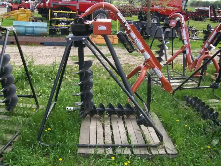Worker using a post hole digger next to a fence line with a freshly dug hole and wooden posts