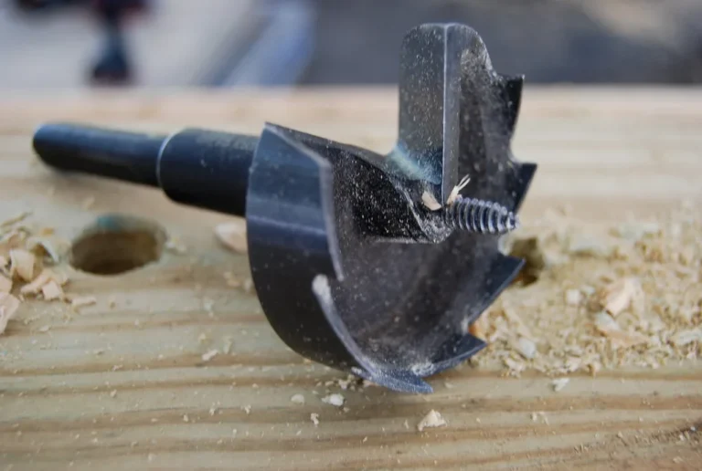 Woodworker comparing a random orbital sander, sanding discs, and a dust hose on a workshop bench