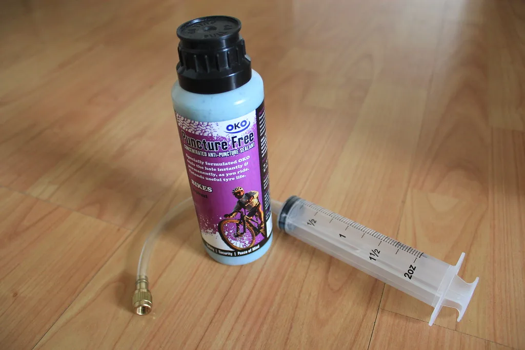Hand brushing UV-protective sealant onto cedar fence slats with visible wood grain