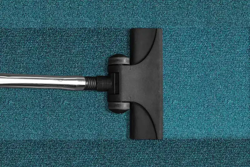 Person vacuuming a hardwood floor with a lightweight vacuum in a sunlit living room