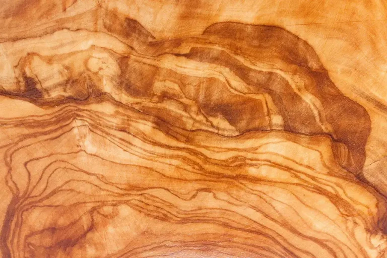 Several wood cutting boards on a kitchen counter beside a knife and chopped herbs.
