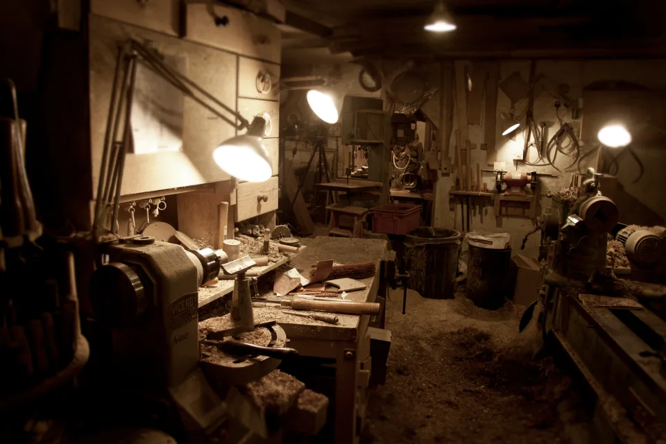 Woodworker comparing a biscuit joiner and a Domino-style joiner beside cabinet parts in natural light