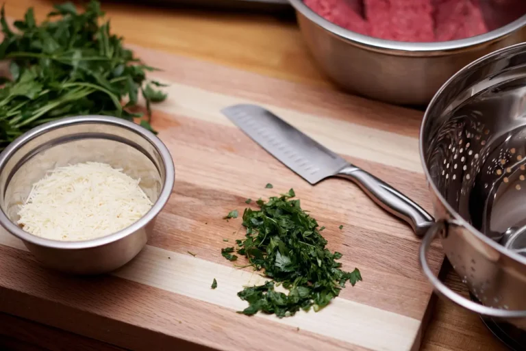 Boardsmith cutting board on a kitchen counter beside a knife and chopped herbs in natural light