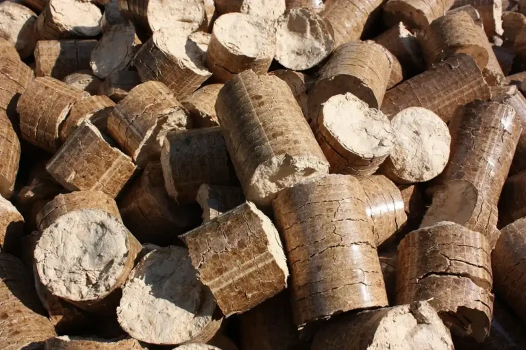 A wood stove beside stacked seasoned firewood while a hand checks a split log with a moisture meter.
