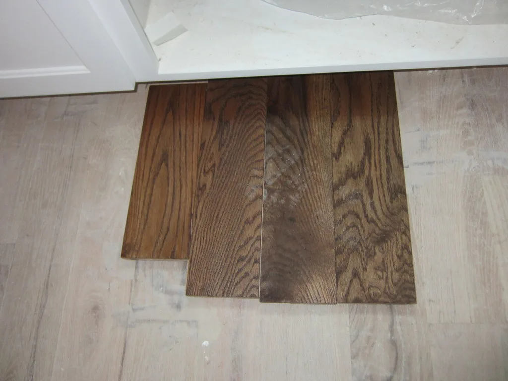 Homeowner and contractor compare hardwood floor samples in a bright living room