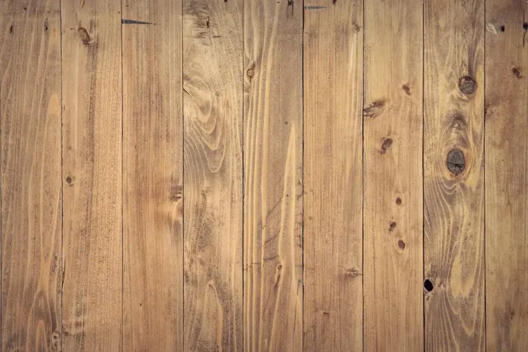 Contractor and homeowner reviewing engineered hardwood planks and tools in a bright living room