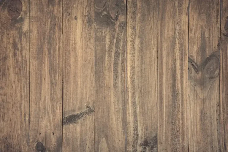 Lumber yard worker measuring stacked redwood boards with a calculator nearby