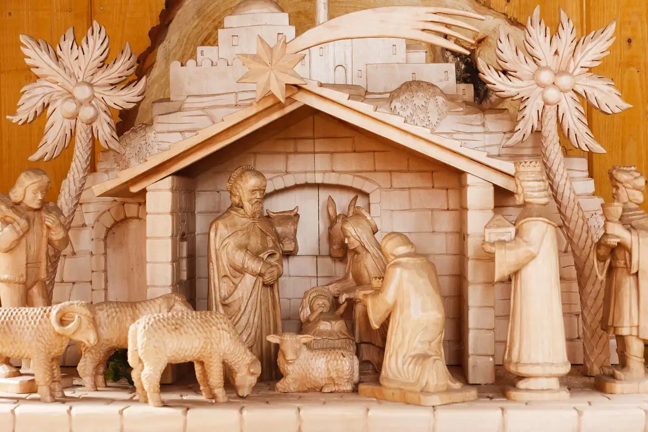 Handcrafted nativity stable made of weathered wood with a pitched roof and straw inside