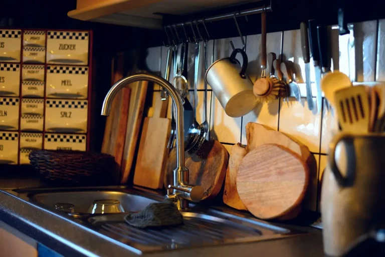 A wooden John Boos cutting board on a kitchen counter with sliced vegetables and a chef's knife