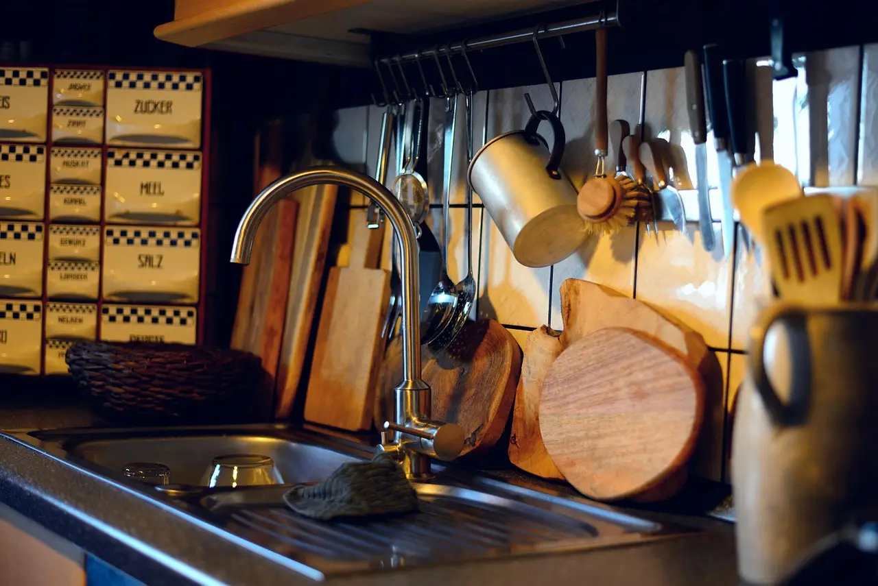 A wooden John Boos cutting board on a kitchen counter with sliced vegetables and a chef's knife