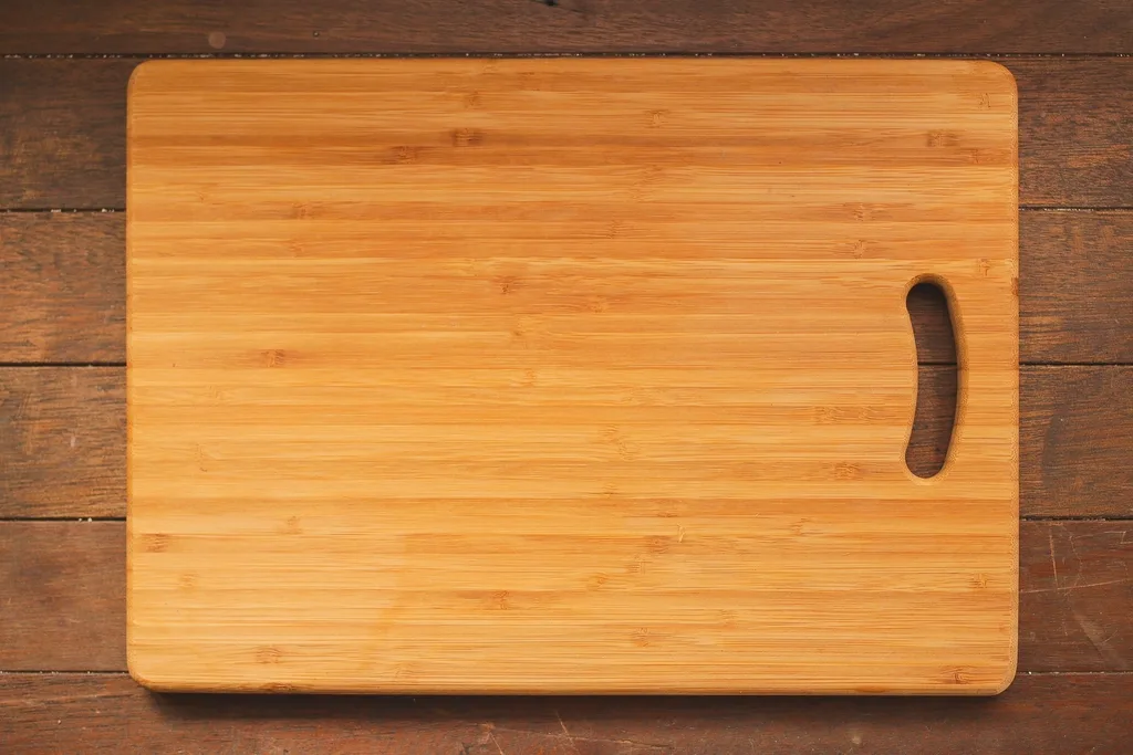 Hands applying oil to a wooden John Boos cutting board beside a bottle of mineral oil