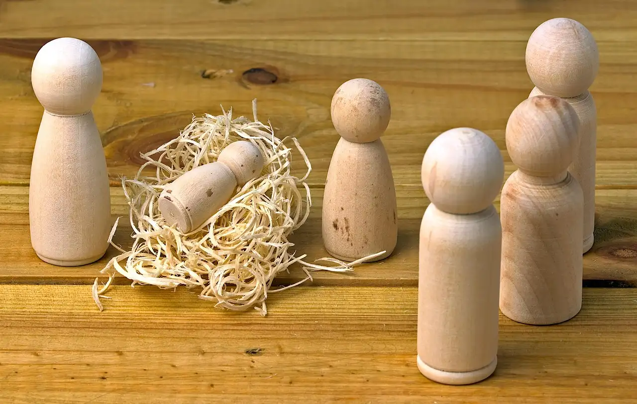 Woodworker comparing nativity patterns for wood beside a jigsaw and scroll saw in a sunlit workshop