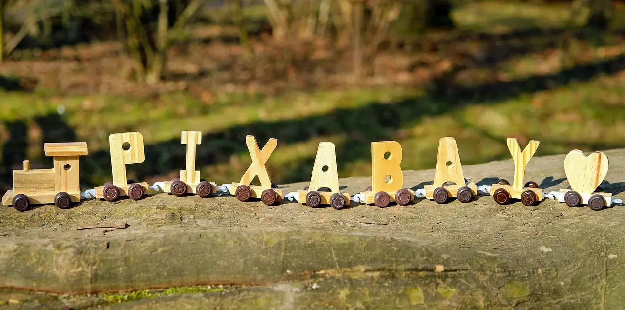 Painted wooden name ornaments, paint brushes, and blank wood pieces arranged on a craft table