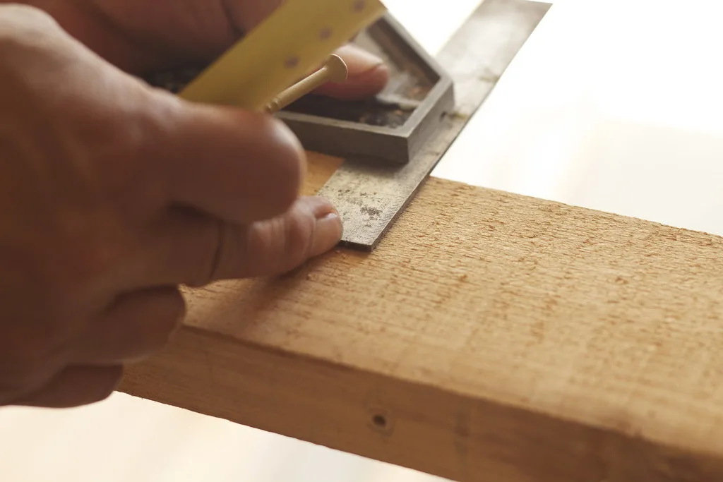 Close-up of a tape measure and pencil marking a cut line on wood