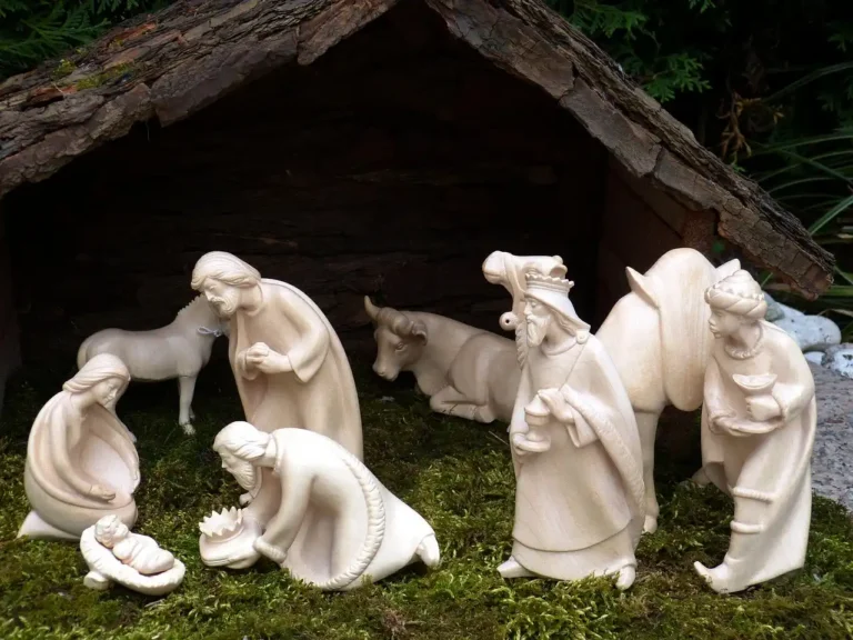 Wooden nativity scene DIY parts laid out on a workshop table with a small stable and tools in natural light.